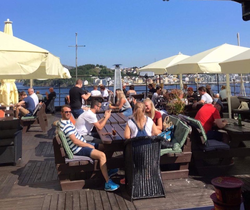 Gjester nyter solen på Taket med utsikt over havna